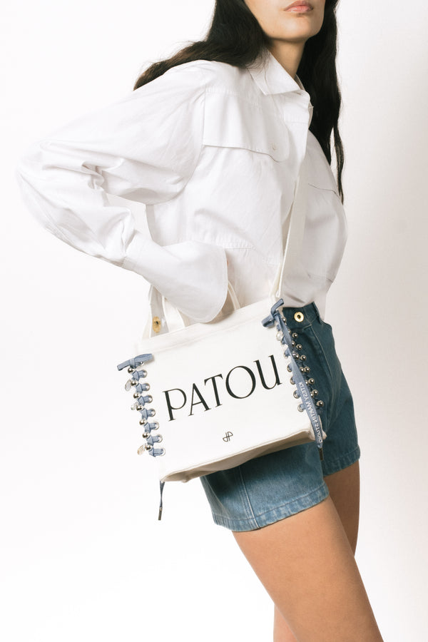 Patou - Patou Upcycling borsa tote in cotone bio - Aurora - For its inaugural edition, Patou partners with French designer Kitesy Martin, founder of Kitesy Martin Studio.Borse tote in cotone bio color panna. Logo Patou e monogramma JP neri. Tracolla bianca con disegni JP in rilievo; bottone oro. Doppia maniglia. Può essere indossata in spalla o portata a mano.Limited Edition.