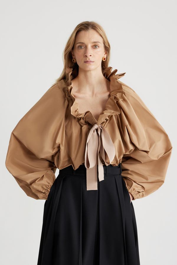 Patou - 재생 파유 아이코닉 드로우스트링 탑 - Gray Sand - 그레이 샌드 컬러의 재생 폴리에스터 파유 소재. 목 부분에서 매듭 짓거나 오프 숄더 스타일로 연출할 수 있는 볼륨감 있는 실루엣. 앞면의 플라운스 주름을 넣은 드로우스트링 칼라, 긴 그로그랭 타이. 신축성 있는 커프스의 배트윙 슬리브. 신축성 있는 허리 부분.