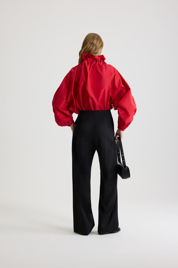 Patou - La Patou Blouse リサイクルファイユ - Lipstick Red - リップスティックレッドのリサイクルポリエステルファイユ製トップス。ネックで結んでもオフショルダーでも着用可能なハイボリューム シルエット。フロントにフラウンスをあしらったドローストリングカラー、ロンググログランタイ付き。袖口に伸縮性があるバットウィングスリーブ。伸縮性があるウエスト。