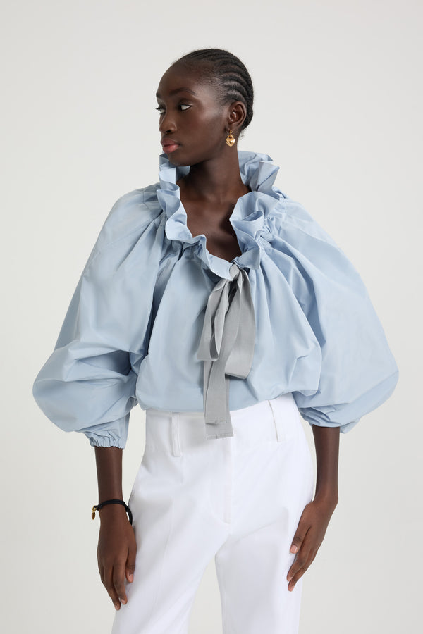 Patou - Iconic drawstring top in recycled faille - Pearl Blue - Pearl Blue recycled polyester faille top. High volume silhouette that can be worn knotted at the neck or off the shoulders. Drawstring collar with flounce at the front and long grosgrain ties. Batwing sleeves with elasticated cuffs. Elasticated waist.