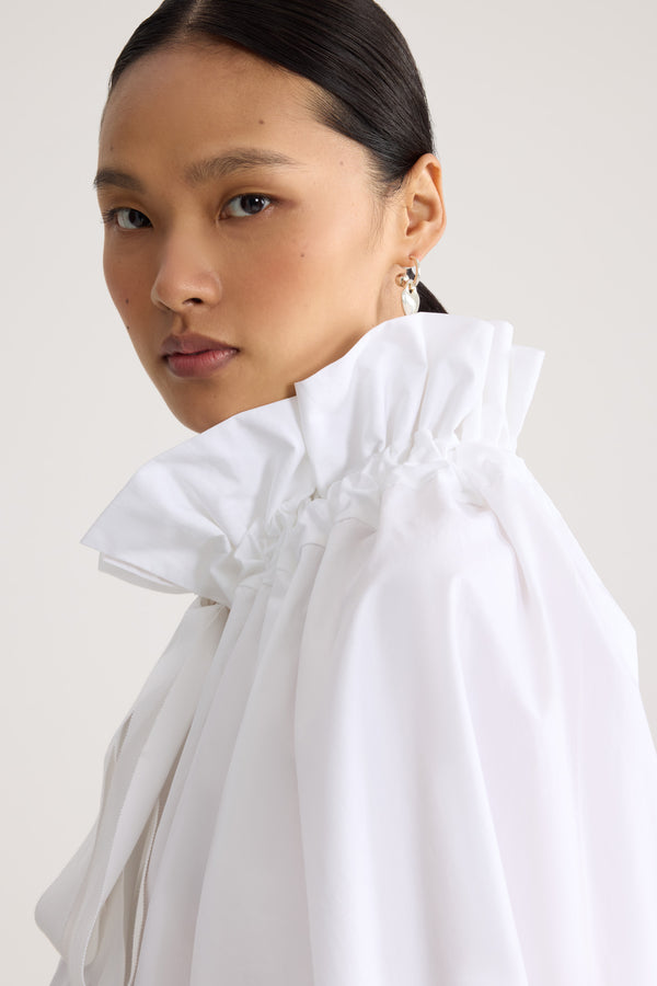 Patou - La Patou Blouse オーガニックコットンポプリン - White - ホワイトのオーガニックコットンポプリン製トップ。ハイボリューム シルエット。ドローストリング カラーにシャーリング&amp;グログラン。袖口に伸縮性があるバットウィングスリーブ。伸縮性があるウエスト。