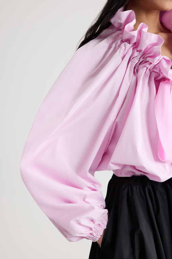 Patou - 오가닉 코튼 포플린 La Patou Blouse - Pink Pearl - 핑크 펄 컬러의 오가닉 코튼 포플린 탑. 목 부분에서 매듭 짓거나 오프 숄더 스타일로 연출할 수 있는 볼륨감 있는 실루엣. 앞면의 플라운스 주름을 넣은 드로우스트링 칼라, 긴 그로그랭 타이. 신축성 있는 커프스의 배트윙 슬리브. 신축성 있는 허리 부분.