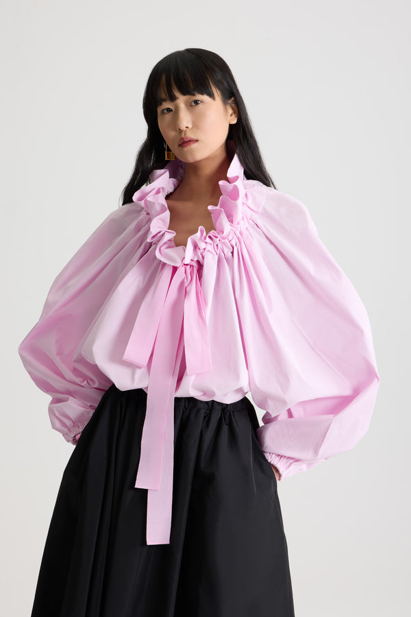 Patou - 오가닉 코튼 포플린 La Patou Blouse - Pink Pearl - 핑크 펄 컬러의 오가닉 코튼 포플린 탑. 목 부분에서 매듭 짓거나 오프 숄더 스타일로 연출할 수 있는 볼륨감 있는 실루엣. 앞면의 플라운스 주름을 넣은 드로우스트링 칼라, 긴 그로그랭 타이. 신축성 있는 커프스의 배트윙 슬리브. 신축성 있는 허리 부분.