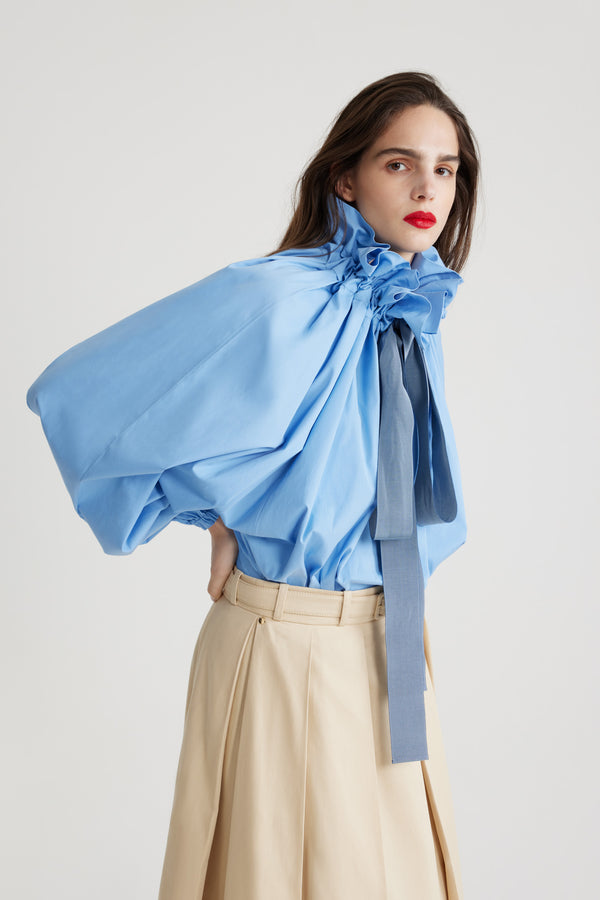 Patou - Iconic drawstring top in organic cotton - Airy Blue - Airy Blue organic cotton poplin top. High volume silhouette that can be worn knotted at the neck or off the shoulders. Drawstring collar with flounce at the front and long grosgrain ties. Batwing sleeves with elasticated cuffs. Elasticated waist.