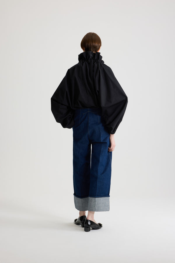 Patou - La Patou Blouse オーガニックコットンポプリン - Black - ブラックのオーガニックコットン製トップ。ネックで結んでもエンボス オフショルダーでも着用可能なハイボリューム シルエット。フロントにフラウンスをあしらったドローストリングカラー、ロンググログランタイ付き。袖口に伸縮性があるバットウィングスリーブ。伸縮性があるウエスト。