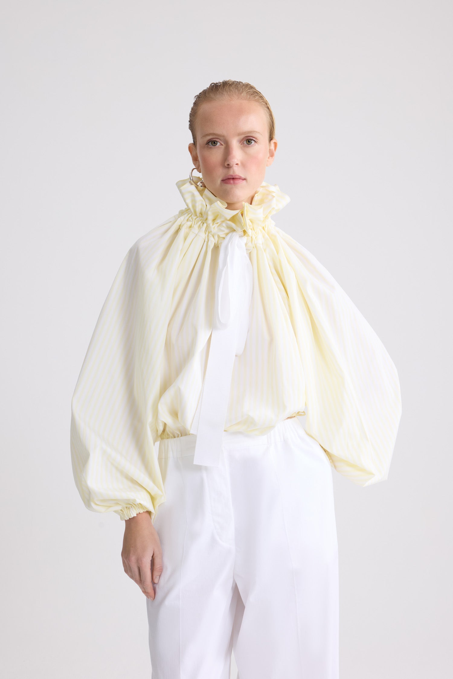 Patou - ストライプ オーガニックコットン アイコニックなボリュームトップス - Lemonade Stripes - イエロー＆ホワイトカラーのストライプ入り オーガニックコットン製 アイコニックなボリュームトップス。際立ったボリューム感のあるシルエット、ネックで結んで、あるいはベアショルダーでまとえます。ギャザー入りフロントにドローストリング付きカラー、グログランのロングタイ。伸縮性のある袖口にバットウィングスリーブ。伸縮性のあるウエスト。