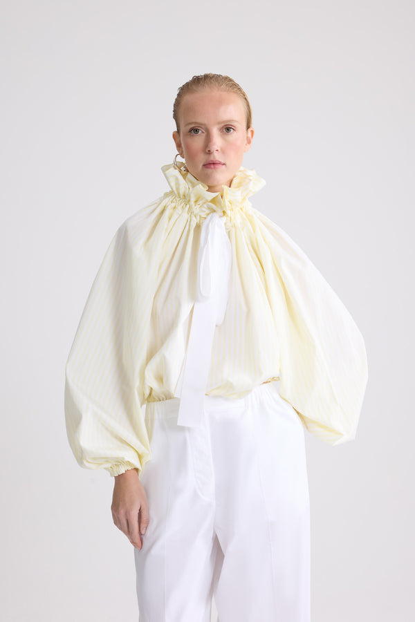 Patou - Top iconico voluminoso a righe in cotone biologico - Lemonade Stripes - Top iconico voluminoso a righe gialle e bianche in cotone biologico. Silhouette molto voluminosa che può être indossata annodata al collo o con le spalle scoperte. Colletto a coulisse con arricciatura frontale e lunghi lacci in gros-grain. Maniche a pipistrello con polsini elasticizzati. Vita elasticizzata.