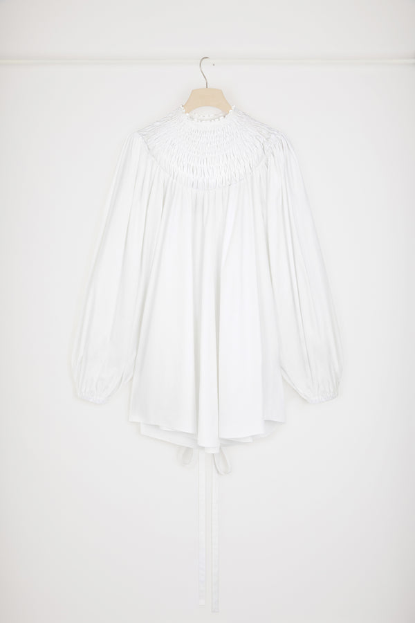 Patou - 오가닉 코튼 스목 칼라 튜닉 - White - 드레스 또는 튜닉? 스타일링 마법을 발휘할 시간입니다.화이트 컬러의 오가닉 코튼 포플린 튜닉. 스목 디테일의 하이 네크라인. 뒷면에 JP 자수 장식. 퍼프 숄더 및 엘라스틱 커프스가 돋보이는 볼륨 슬리브. 앞 또는 뒤로 묶을 수 있는 허리 부분의 탈부착 가능한 벨트. 미니원피스로 착용이 가능합니다.