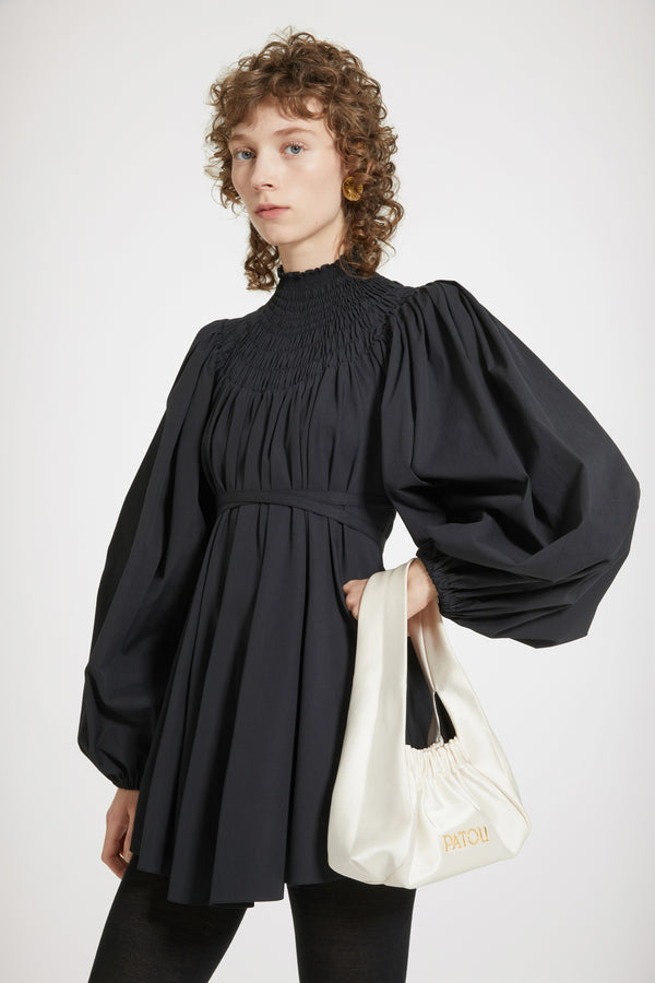 Patou - 오가닉 코튼 스목 칼라 튜닉 - Black - 드레스 또는 튜닉? 스타일링 마법을 발휘할 시간입니다.블랙 컬러의 오가닉 코튼 포플린 튜닉. 스목 디테일의 하이 네크라인. 뒷면에 JP 자수 장식. 퍼프 숄더 및 엘라스틱 커프스가 돋보이는 볼륨 슬리브. 앞 또는 뒤로 묶을 수 있는 허리 부분의 탈부착 가능한 벨트. 미니원피스로 착용이 가능합니다.