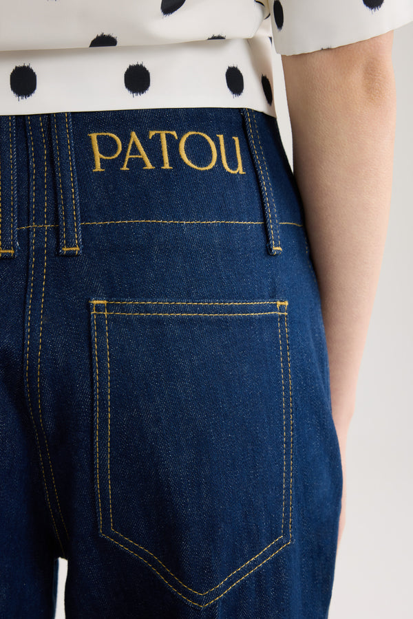 Patou - Pantalon à ceinture large en denim de coton - Rodeo Blue - Pantalon en denim de coton bleu rodéo. Taille mi-haute à basse. Jambe droite. Passants de ceinture. Fermeture par bouton doré gravé Patou et zip dissimulé à l’avant. Poches latérales. Pli pressé sur le devant.