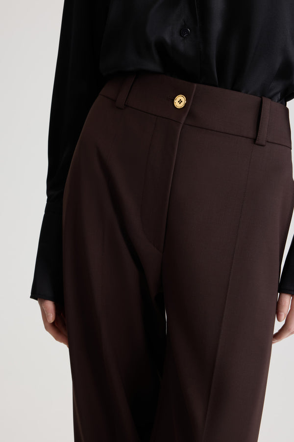 Patou - サステナブルテクニカルウール フレア テーラードパンツ - Smoked Ebony - スモークドエボニーのサステナブルなテクニカルウールツイルパンツ。長めのフレアレッグ。フロントにゴールドトーンのJPモノグラム刻印入りボタンと隠しファスナー。ベルトループ付き。サイドにポケット。前面と背面にステッチクリース。
