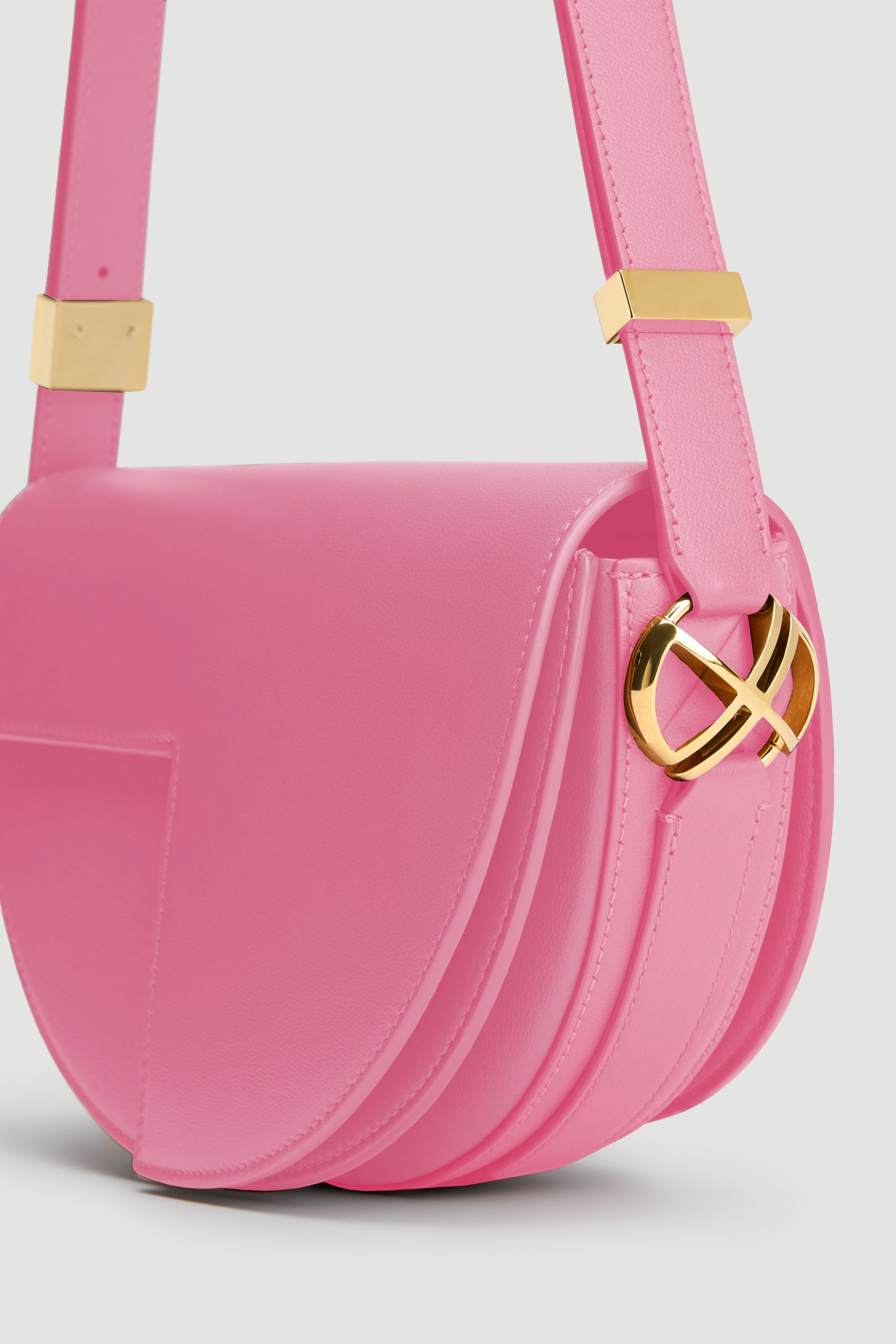 Patou - Le Patou - Pink - Le Patou a plus d&amp;#39;un tour dans son sac !Sac en cuir rose. Édition limitée et numérotée disponible en 60 exemplaires. Forme demi-lune avec découpes géométriques inspirée du monogramme JP. Pièces en métal doré avec détail JP inspiré d&amp;#39;une broche des archives Jean Patou. Bandoulière ajustable permettant un porté épaule, en bandoulière ou à la main. Fermeture aimantée avec détail JP doré. Compartiments multiples à l&amp;#39;intérieur.Dimensions : 25 cm de longueur, 15 cm de hauteur et 6 cm de profondeur.Bandoulière ajustable en 3 longueurs : 47 cm (sur l&amp;#39;épaule), 36 cm (en bandoulière), 28 cm (porté à la main)