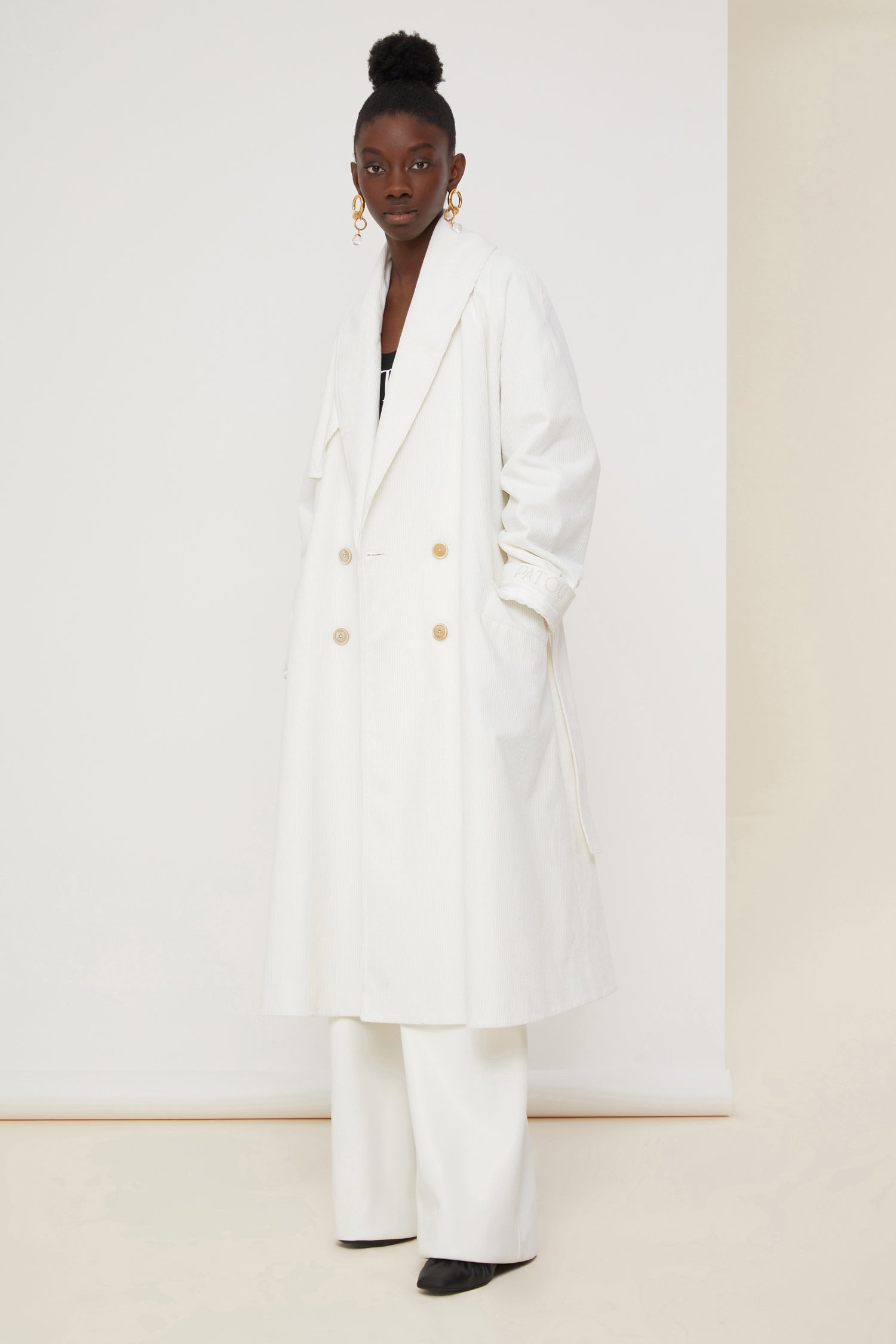 Patou - Corduroy trenchcoat - Pearl - A tailoring classic with a soft velvet touch.Signature Patou trenchcoat in pearl white corduroy. Double-breasted style with a slight A-line silhouette. Button fastening and belted waist. Two pockets at the sides. Fully lined.