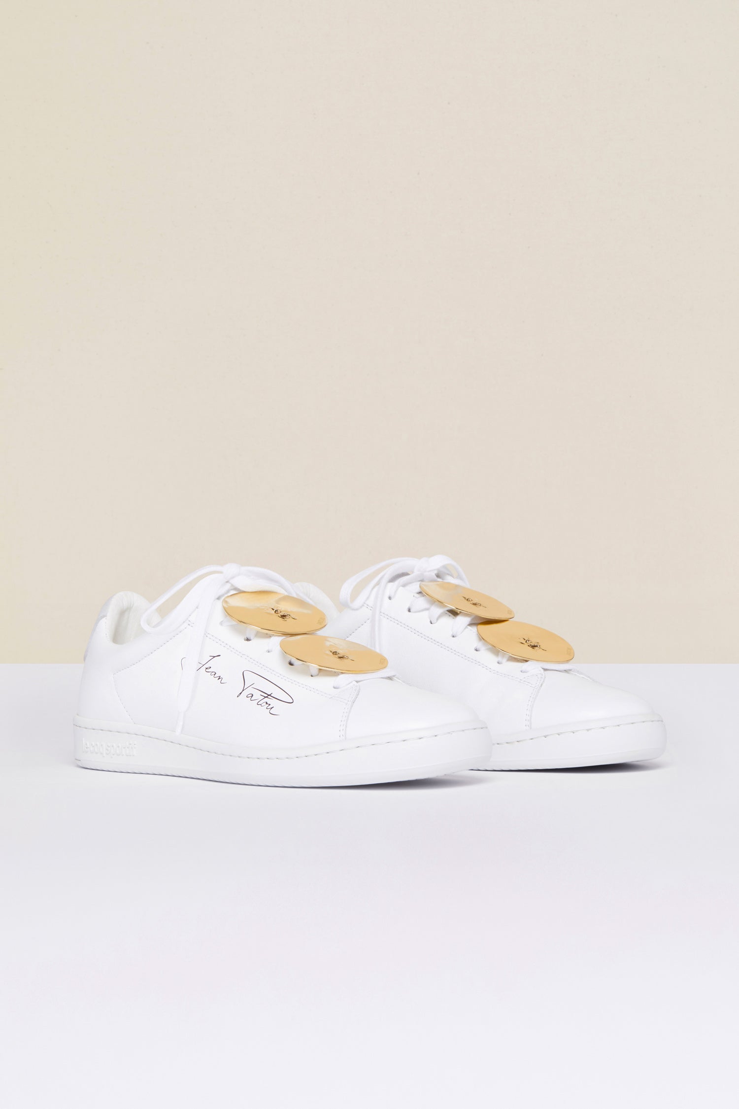 Patou - Jewellery low top sneakers - White Jewellery - A golden touch that’s totally Patou!As part of an ongoing collaboration with Le Coq Sportif. White low top sneakers with black Jean Patou signature on the side and embroidered Le Coq Sportif logo at the back. Rounded toecap. Lace-up style with “Bocca della Verità” embellishments in gold-coloured brass.