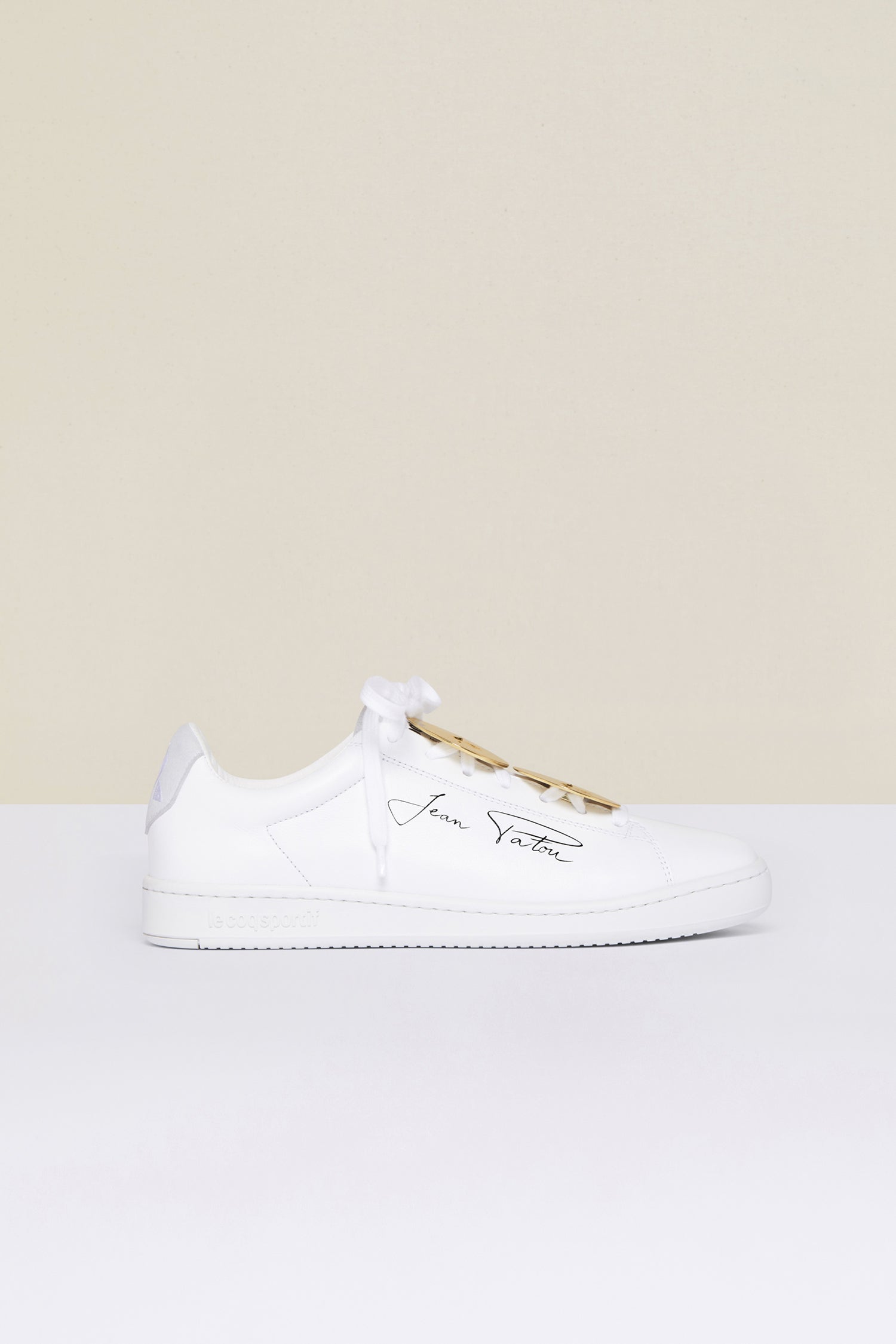 Patou - Jewellery low top sneakers - White Jewellery - A golden touch that’s totally Patou!As part of an ongoing collaboration with Le Coq Sportif. White low top sneakers with black Jean Patou signature on the side and embroidered Le Coq Sportif logo at the back. Rounded toecap. Lace-up style with “Bocca della Verità” embellishments in gold-coloured brass.