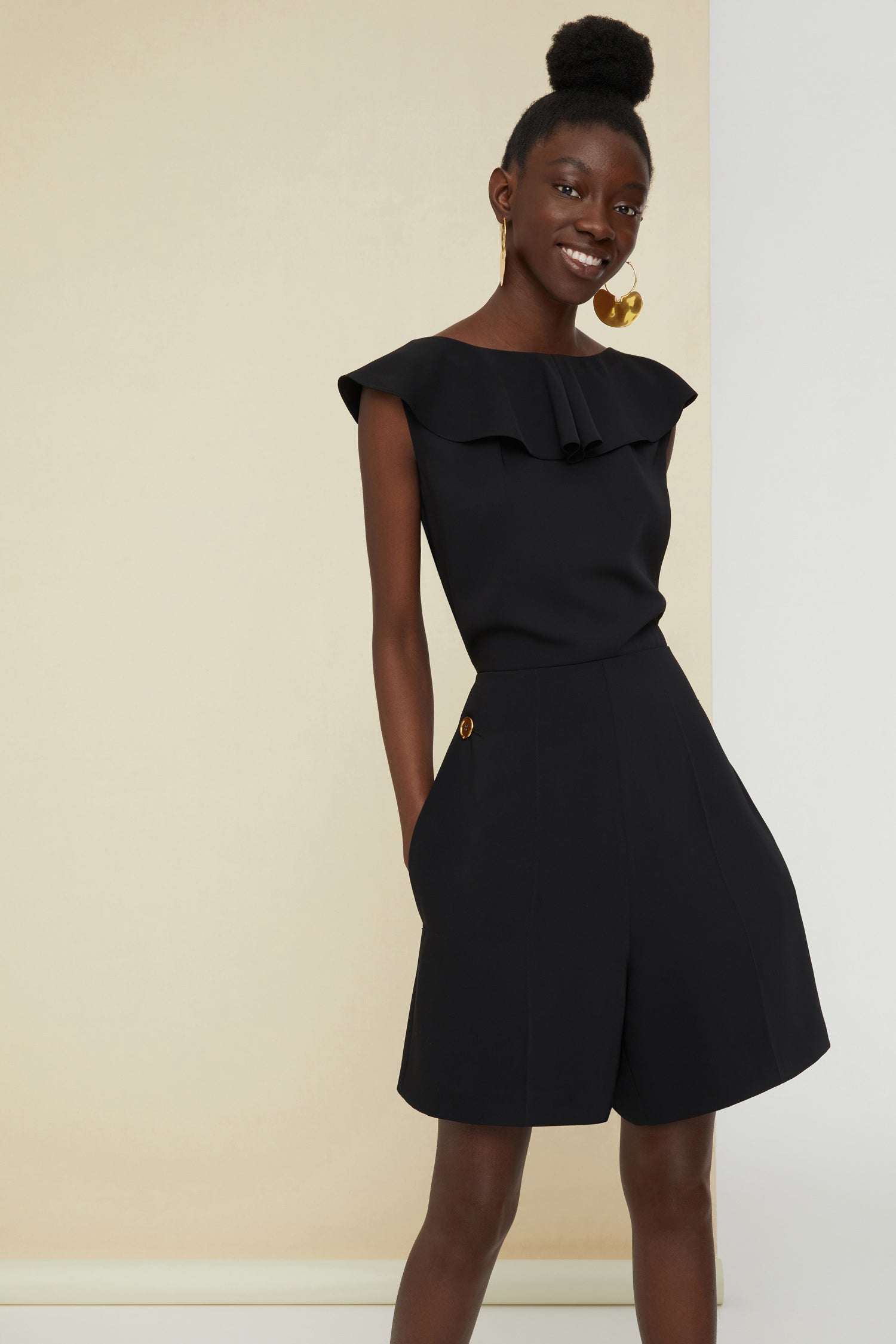 Patou - Jumpsuit mit Cut-Outs hinten. - Black - Abendliche Architektur in Schwarz.  Schwarzer Jumpsuit aus Cady mit körpernahem Schnitt und gerüschtem Halsausschnitt. Gedrehte Rückseite mit Cut-Outs. Goldfarbene Knöpfe mit Gravur, zwei hinten, zwei an den Hüften. Verdeckter seitlicher Reißverschluss.