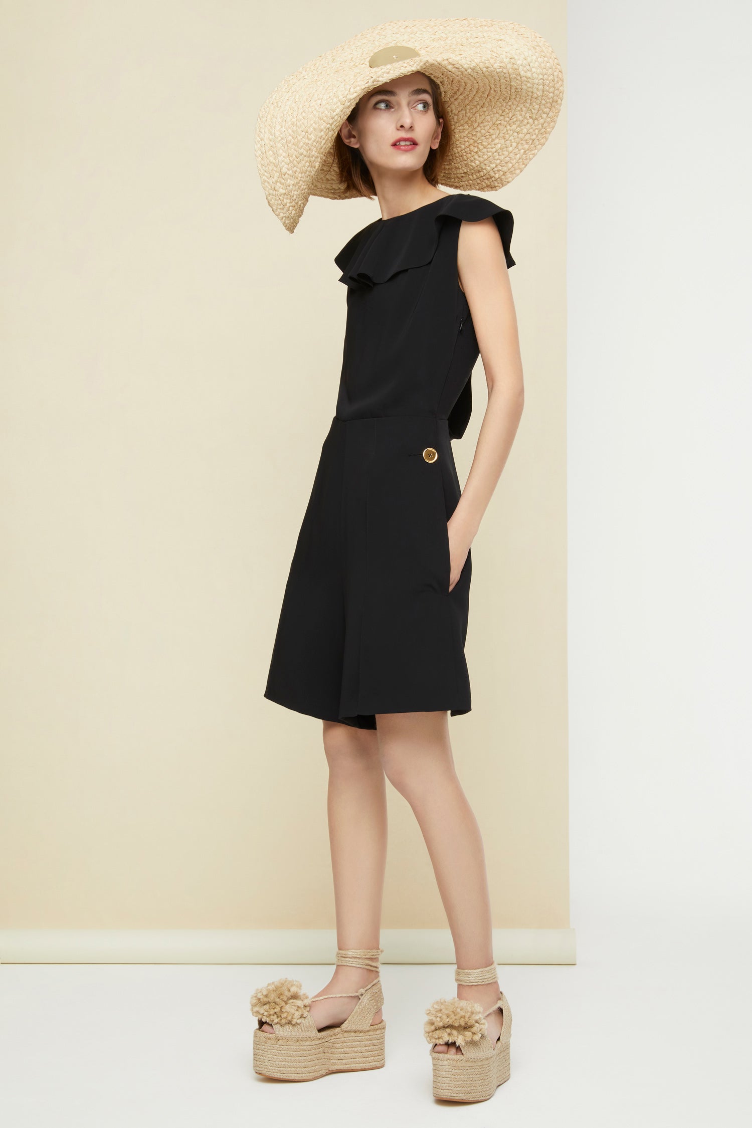 Patou - Jumpsuit mit Cut-Outs hinten. - Black - Abendliche Architektur in Schwarz.  Schwarzer Jumpsuit aus Cady mit körpernahem Schnitt und gerüschtem Halsausschnitt. Gedrehte Rückseite mit Cut-Outs. Goldfarbene Knöpfe mit Gravur, zwei hinten, zwei an den Hüften. Verdeckter seitlicher Reißverschluss.