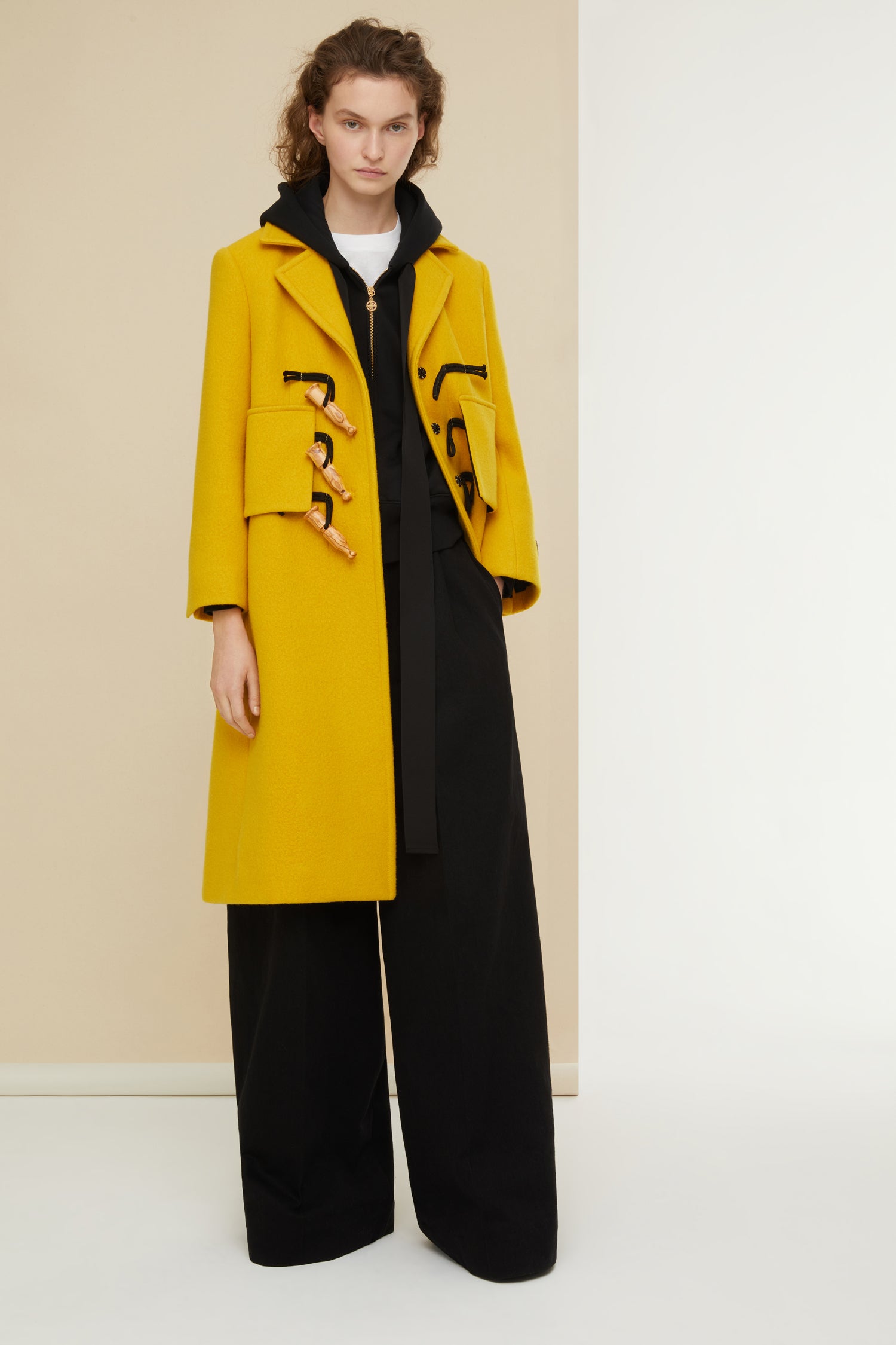 Patou - Manteau appeau en laine et cachemire recyclés - Saffron - L’appeau s’invite sur le manteau.Manteau en mélange laine et cachemire jaune safran. Silhouette longue et légèrement évasée. Fermeture par boutons en bois de style appeau ainsi que par des pressions cachées. Deux grandes fausses poches à rabat ; deux poches sur les côtés. Étiquette Patou brodée sur la manche gauche.