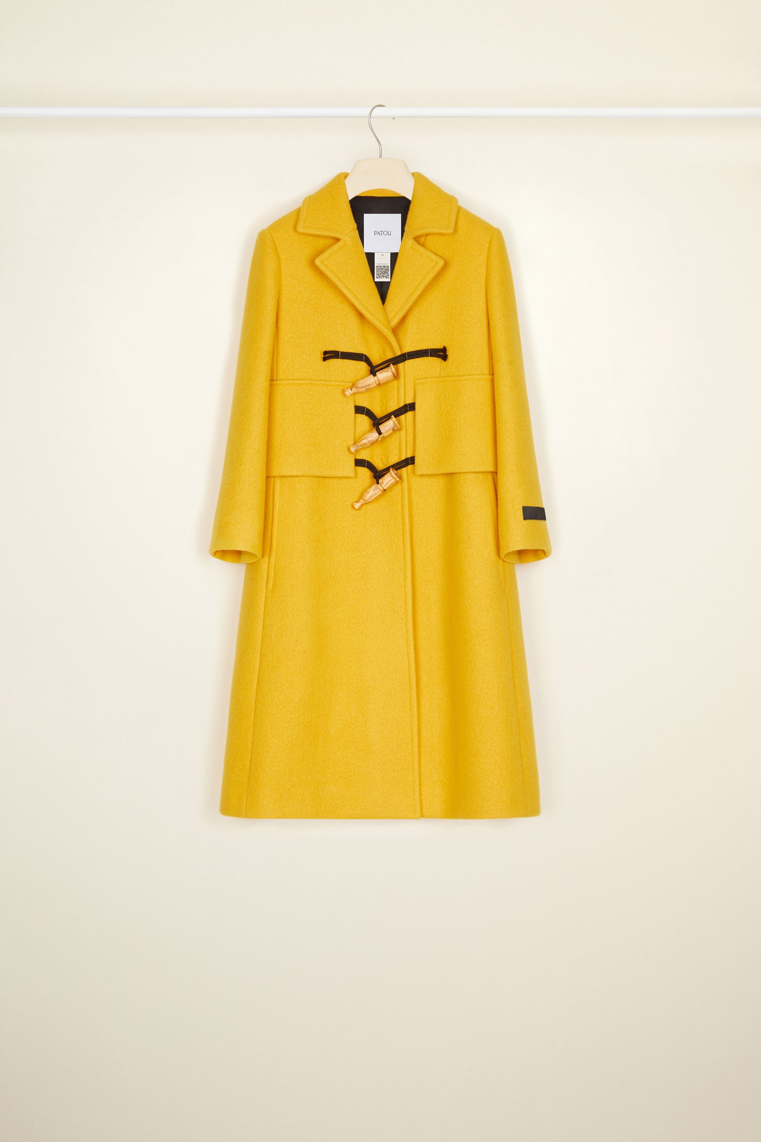 Patou - Manteau appeau en laine et cachemire recyclés - Saffron - L’appeau s’invite sur le manteau.Manteau en mélange laine et cachemire jaune safran. Silhouette longue et légèrement évasée. Fermeture par boutons en bois de style appeau ainsi que par des pressions cachées. Deux grandes fausses poches à rabat ; deux poches sur les côtés. Étiquette Patou brodée sur la manche gauche.