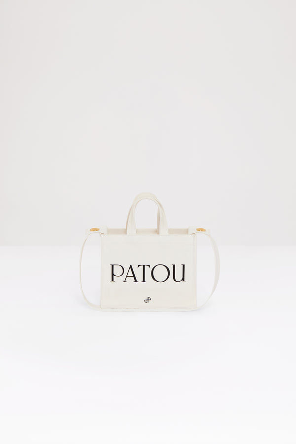 Patou - 오가닉 코튼 스몰 파투 캔버스 토트백 - Cream - 크림 컬러의 오가닉 코튼 소재. Patou 레터링 로고, 블랙 JP 모노그램 장식. 한쪽 측면에 골드 버튼, 반대편에 사이즈 조절이 가능한 매듭 리본이 있는 엠보싱 처리된 화이트 숄더 스트랩. 두 개의 탑 핸들. 토트백 또는 숄더백으로 착용 가능.