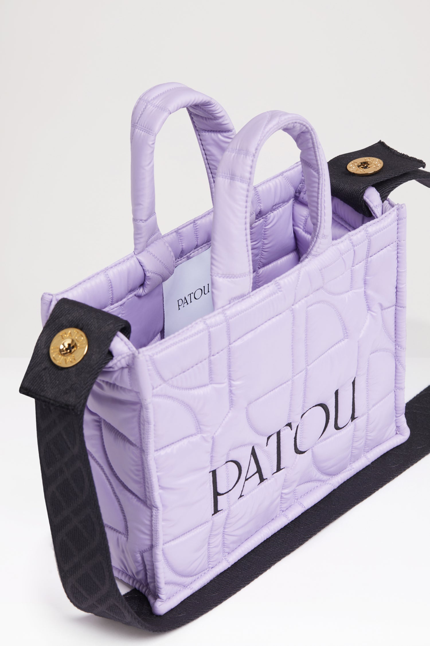 Patou - 스몰 파투 퀼티드 토트백 - Lavender - 어디든 휴대하기 쉬운 파투의 토트백. 라벤더 컬러 폴리아미드 소재 토트백. JP 올오버 퀼팅. 블랙 컬러의 Patou 레터링 로고. Patou가 새겨진 골드 버튼으로 양쪽 측면에 부착된 블랙 컬러의 엠보싱 숄더 스트랩. 두 개의 탑 핸들. 토트백 또는 숄더백으로 착용 가능.