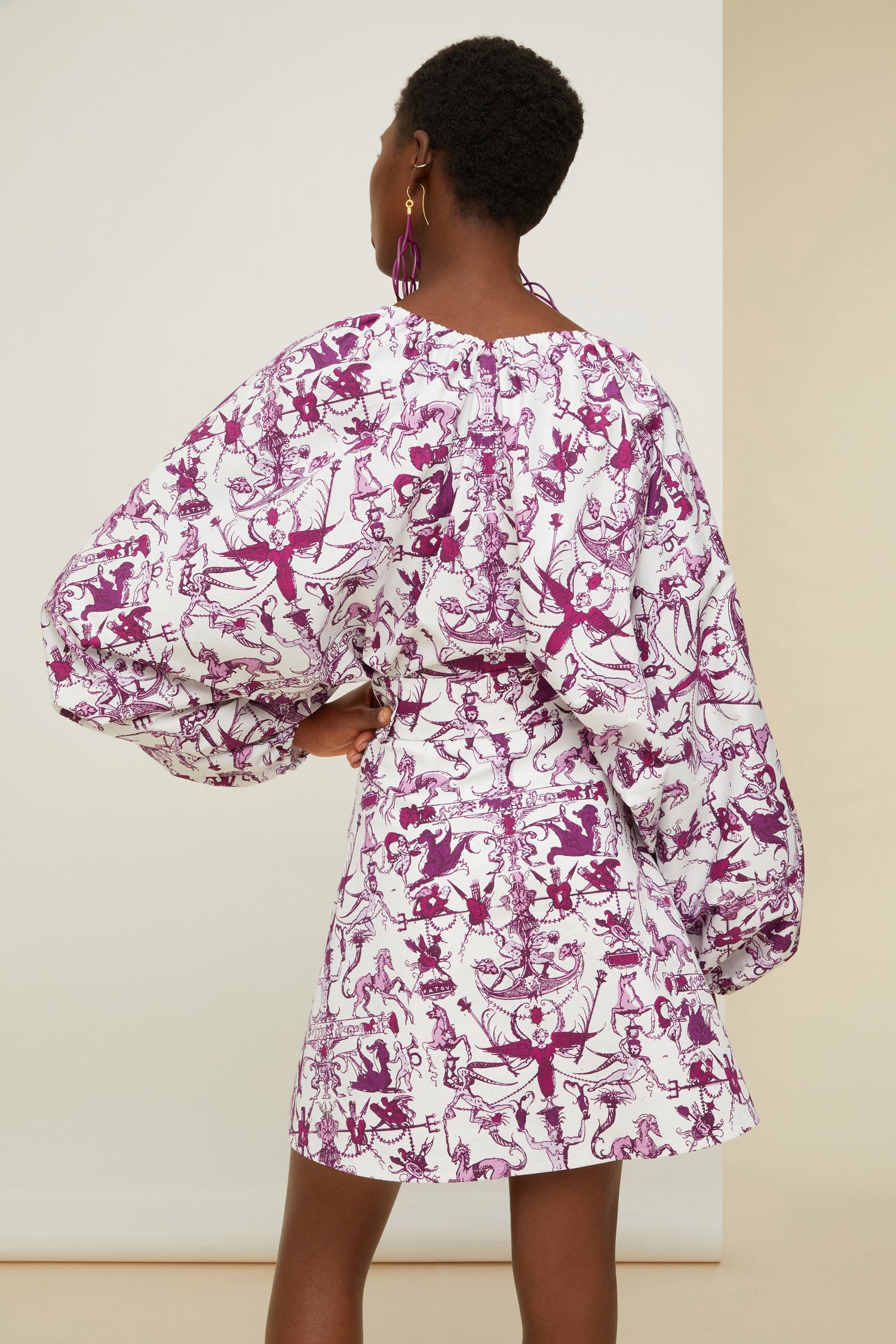 Patou - Elastisches Minikleid aus bedruckter Bio-Baumwolle - Stories And Tales - Eine Geschichte über kurze Säume und großes Volumen.  Kleid aus Bio-Baumwollpopeline mit dem „Stories and Tales“-Print der Saison. Kurz geschnitten. Elastischer V-Ausschnitt und Rücken. Voluminöse Ärmel mit elastischen Ärmelabschlüssen. Breiter größenverstellbarer Taillengürtel aus Stoff mit stoffbezogener Schließe und farblich abgestimmter Patou Logostickerei. Rockteil mit A-Linien-Schnitt.