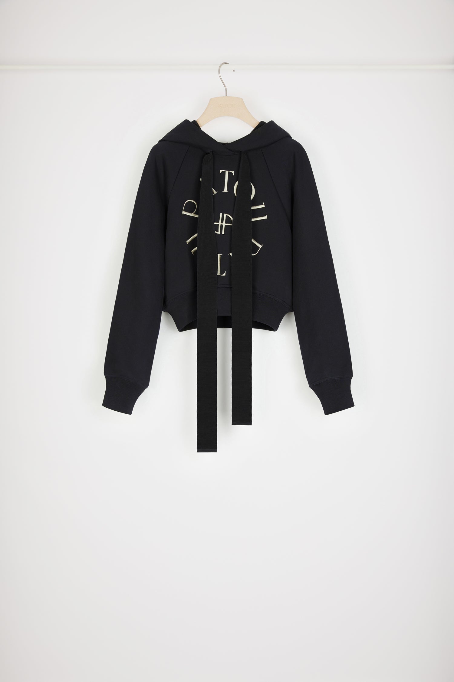 Patou - Felpa corta con logo medaglione in cotone bio - Black - Variazione di stagione sulla felpa Patou.Felpa in cotone bio nero. Modello corto. Collo con cappuccio e lacci in grosgrain. Logo Patou medaglione ricamato sul davanti. Maniche raglan. Polsini e vita a costine.