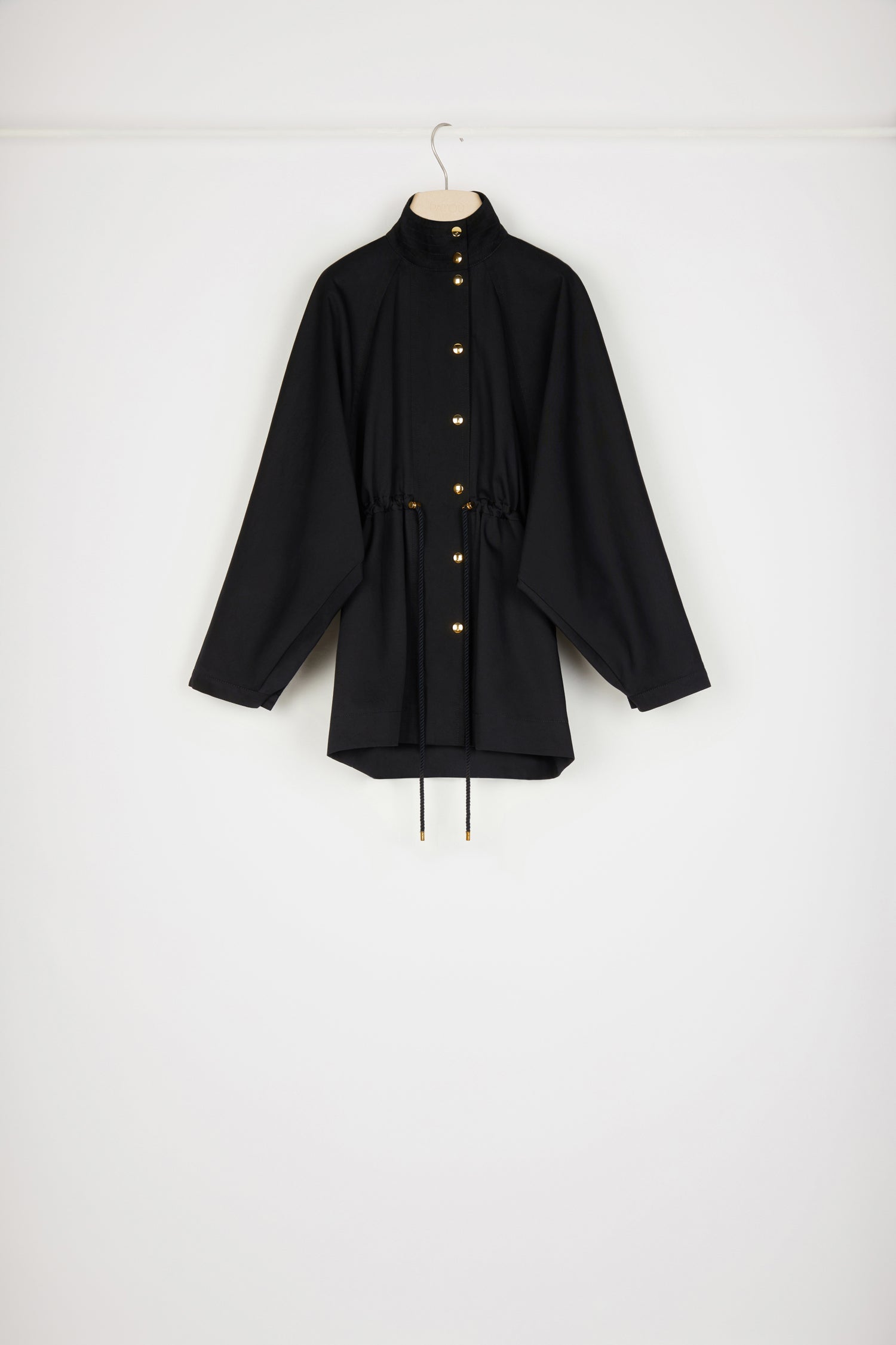 Patou - Parka en gabardine bio - Black - Une parka Patou que l&amp;#39;on aime plus que tout.Parka en gabardine de coton bio noir. Silhouette ample. Col montant avec détail de surpiqûres. Boutons pression dorés décentrés. Manches raglan chauve-souris avec pli au poignet. Taille coulissé avec liens en corde et détails en métal doré. Poches dans les coutures latérales. Patou et monogramme JP brodés au dos.