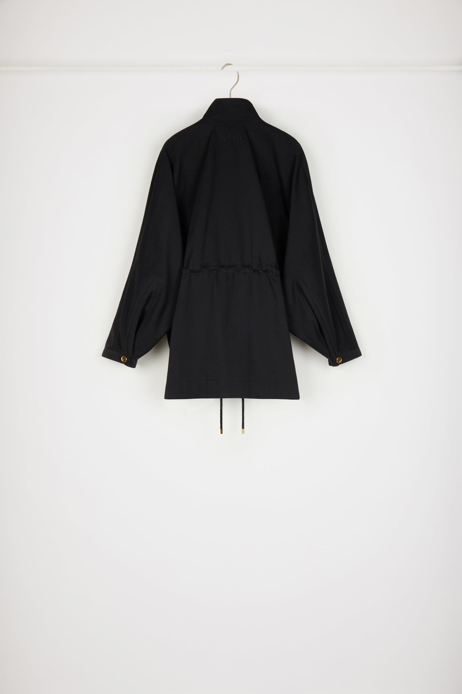 Patou - Parka en gabardine bio - Black - Une parka Patou que l&amp;#39;on aime plus que tout.Parka en gabardine de coton bio noir. Silhouette ample. Col montant avec détail de surpiqûres. Boutons pression dorés décentrés. Manches raglan chauve-souris avec pli au poignet. Taille coulissé avec liens en corde et détails en métal doré. Poches dans les coutures latérales. Patou et monogramme JP brodés au dos.