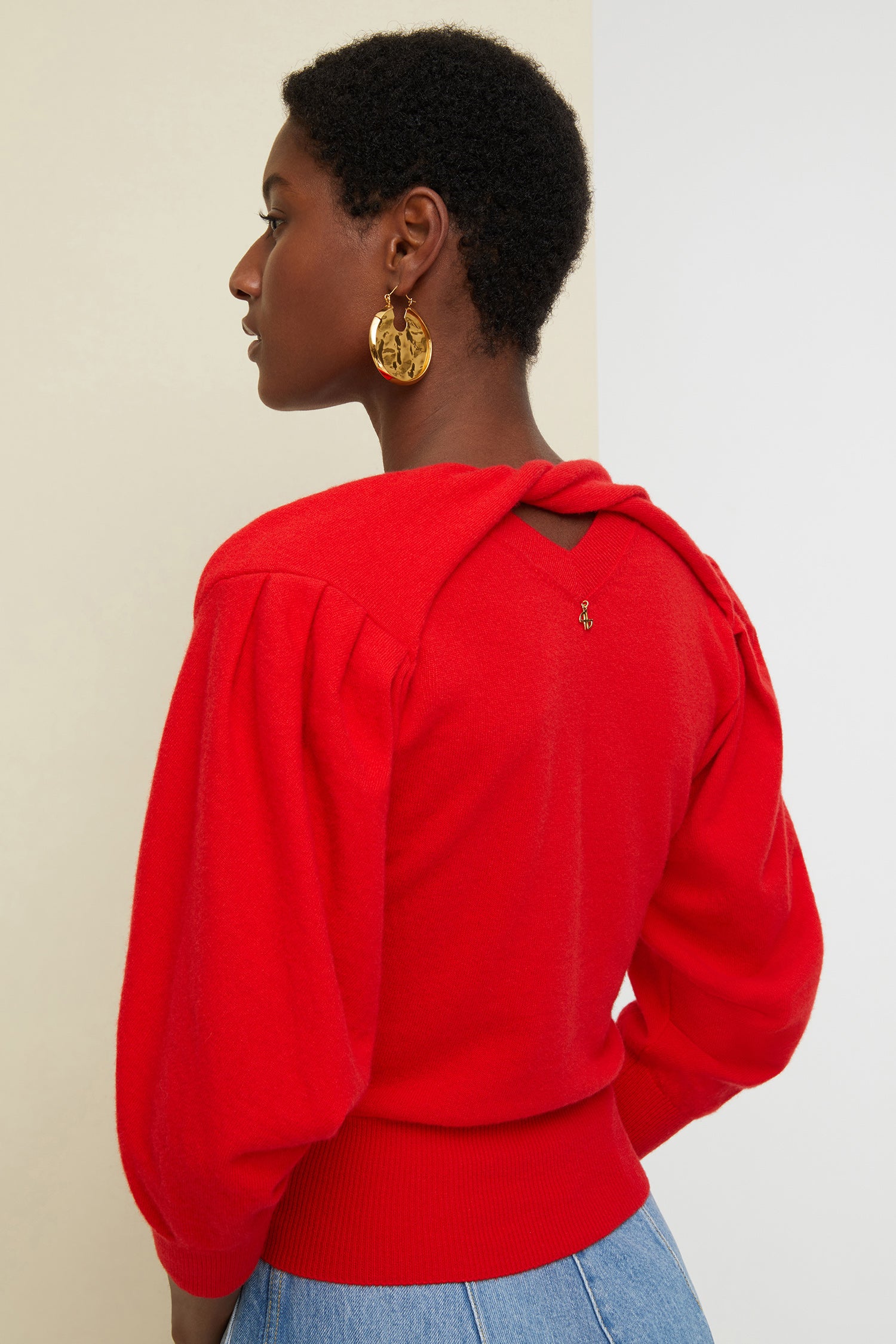 Patou - Wollpullover mit gedrehtem Kragen - Poppy - Strick in Bewegung.Mohnroter Wollpullover. V-Ausschnitt, hinten gedrehter Kragen. Goldfarbenes JP-Monogramm. Verkürzte, drapierte Ärmel.