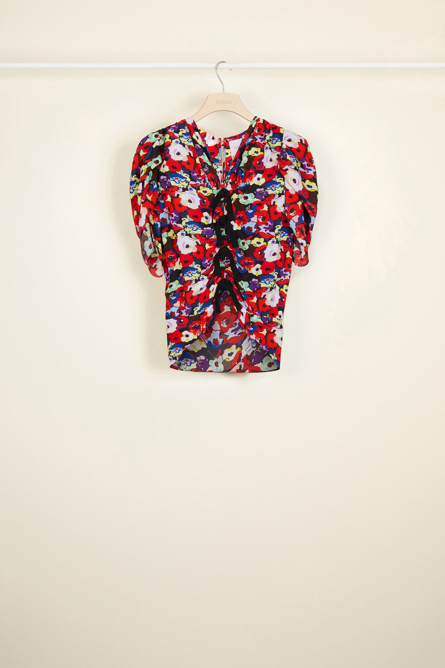 Patou - Blümchen-Top mit Rüschen und Schleifen - A Thousand Flowers Bloom Print - Blüten und Schleifen.Gerüschtes Oberteil mit dem charakteristischen „A Thousand Flowers Bloom&amp;quot;-Print dieser Saison. Mehrere schwarze Schleifen auf der Vorderseite. Kurze Tulpenärmel. Knopfverschluss hinten. Asymmetrischer Saum.