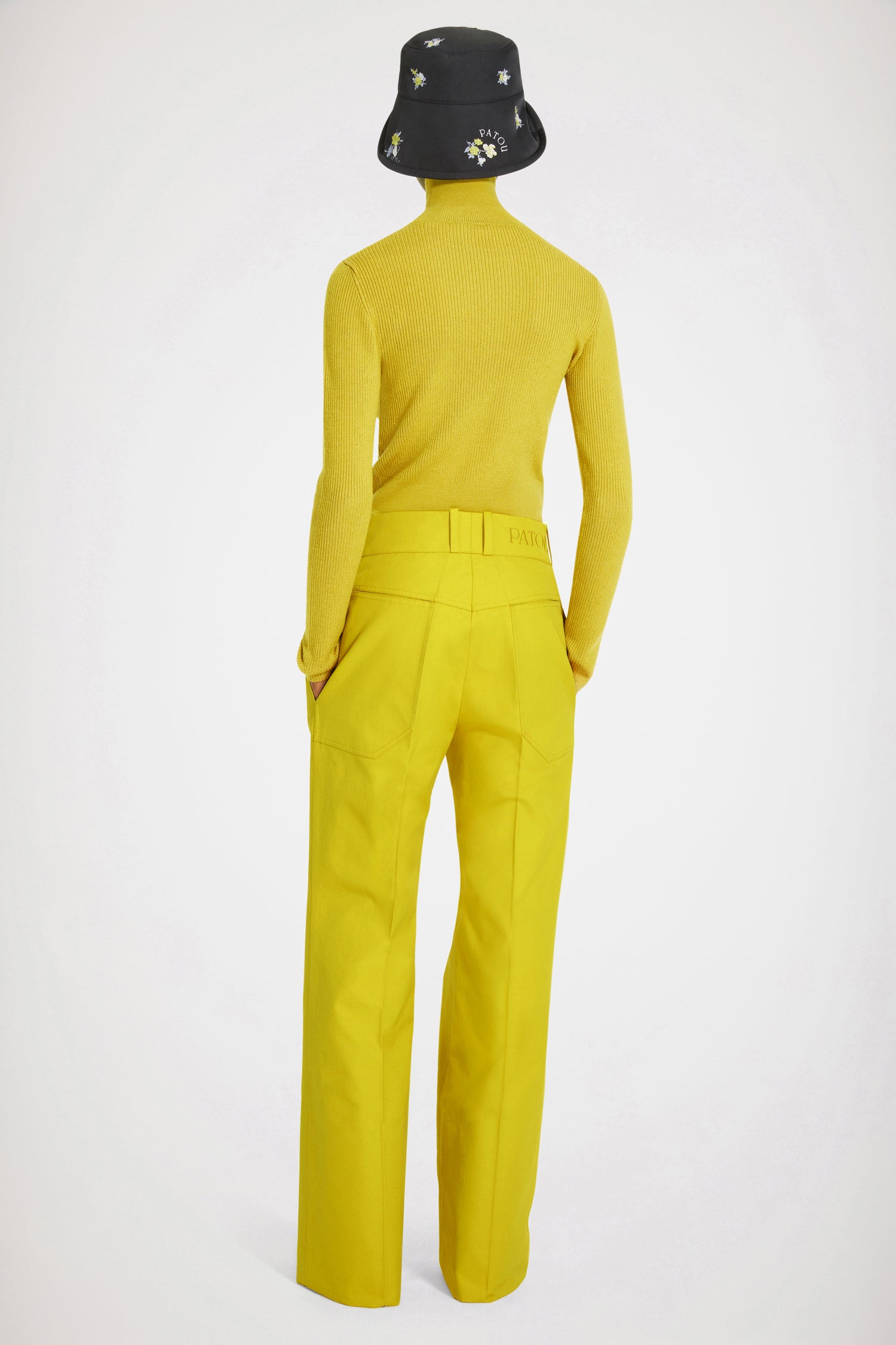 Patou - Flared trousers in organic cotton - Absinthe - Low rise, high craftsmanship: the perfect Patou trousers. Absinthe yellow organic cotton canvas trousers. Slightly flared straight leg with crease at the front and back. Low rise. Gold-tone Patou engraved button fastening at the front. Belt loops. Patou logo embroidered at the back. Pockets at the sides. Wide pockets at the back to complement the Eiffel tower construction.