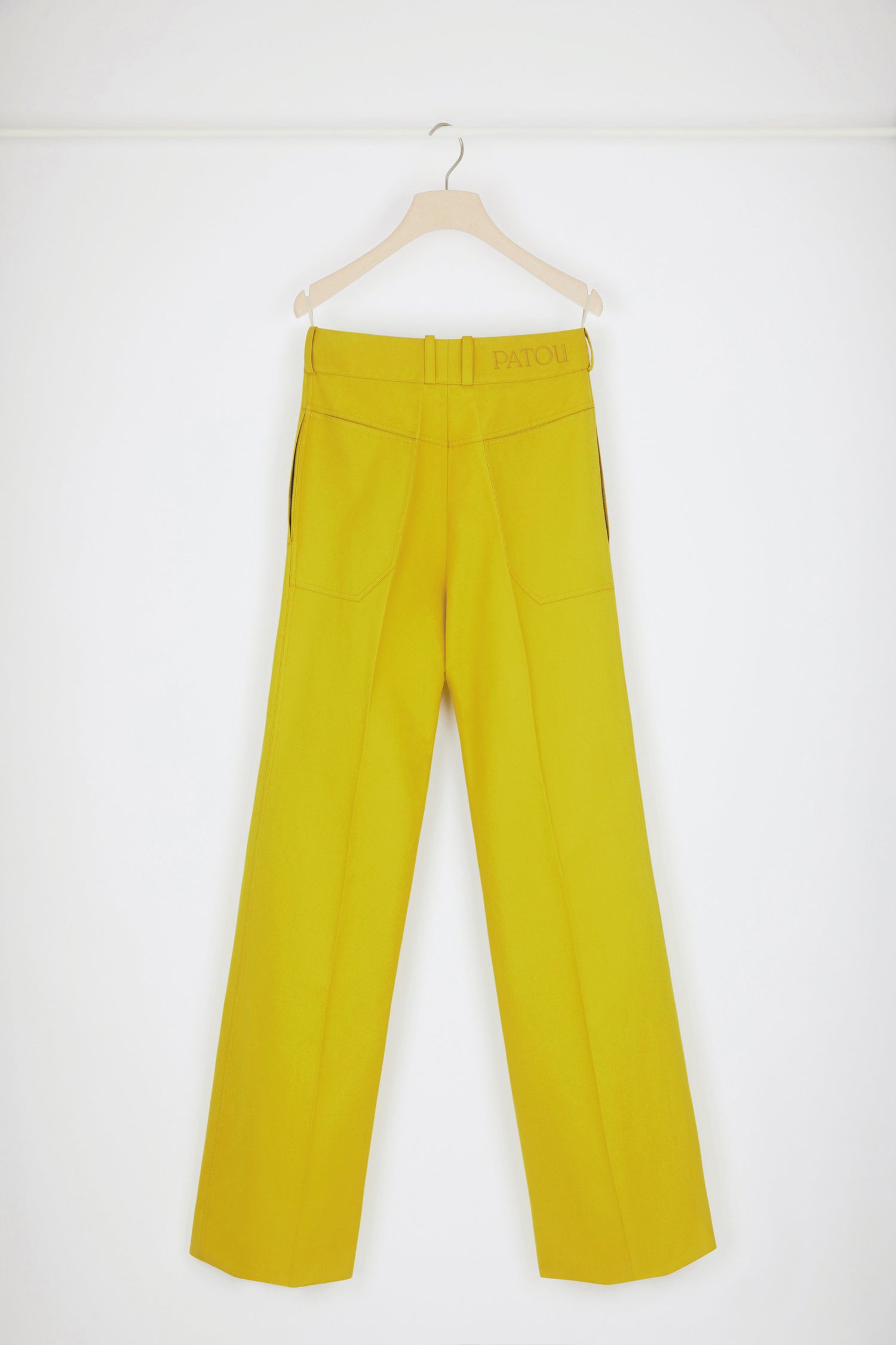 Patou - Flared trousers in organic cotton - Absinthe - Low rise, high craftsmanship: the perfect Patou trousers. Absinthe yellow organic cotton canvas trousers. Slightly flared straight leg with crease at the front and back. Low rise. Gold-tone Patou engraved button fastening at the front. Belt loops. Patou logo embroidered at the back. Pockets at the sides. Wide pockets at the back to complement the Eiffel tower construction.