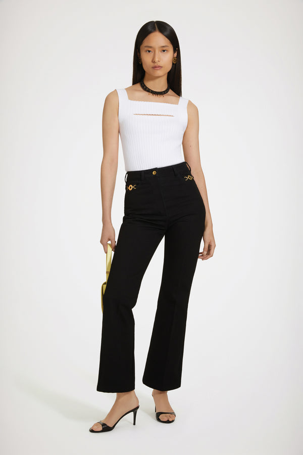 Patou - オーガニックコットンデニム製 フレアーパンツ - Black - ジャン・パトゥのアートが昇華された新しいパトゥデニム。ブラックカラーのオーガニックコットンデニム製パンツ。フレアーカット。ミッドライズ。フロントにゴールドトーンのパトゥ刻印入りボタン。ベルトループ付き。ウエストバンドにパトゥの刺しゅうロゴ。フロントとバックにダーツ使いとセンター位置の折り目。フロントにゴールドカラーのJP刻印入りオーナメントをあしらったポケット2つ。バックにブランドを象徴するカーブシーム。The ornament can be removed.